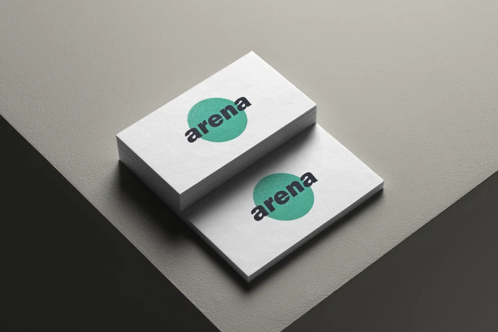 Close-up of stacked white business cards with a vibrant green "arena" logo, showcasing the tactile raised ink texture and crisp edges available at our print studio.