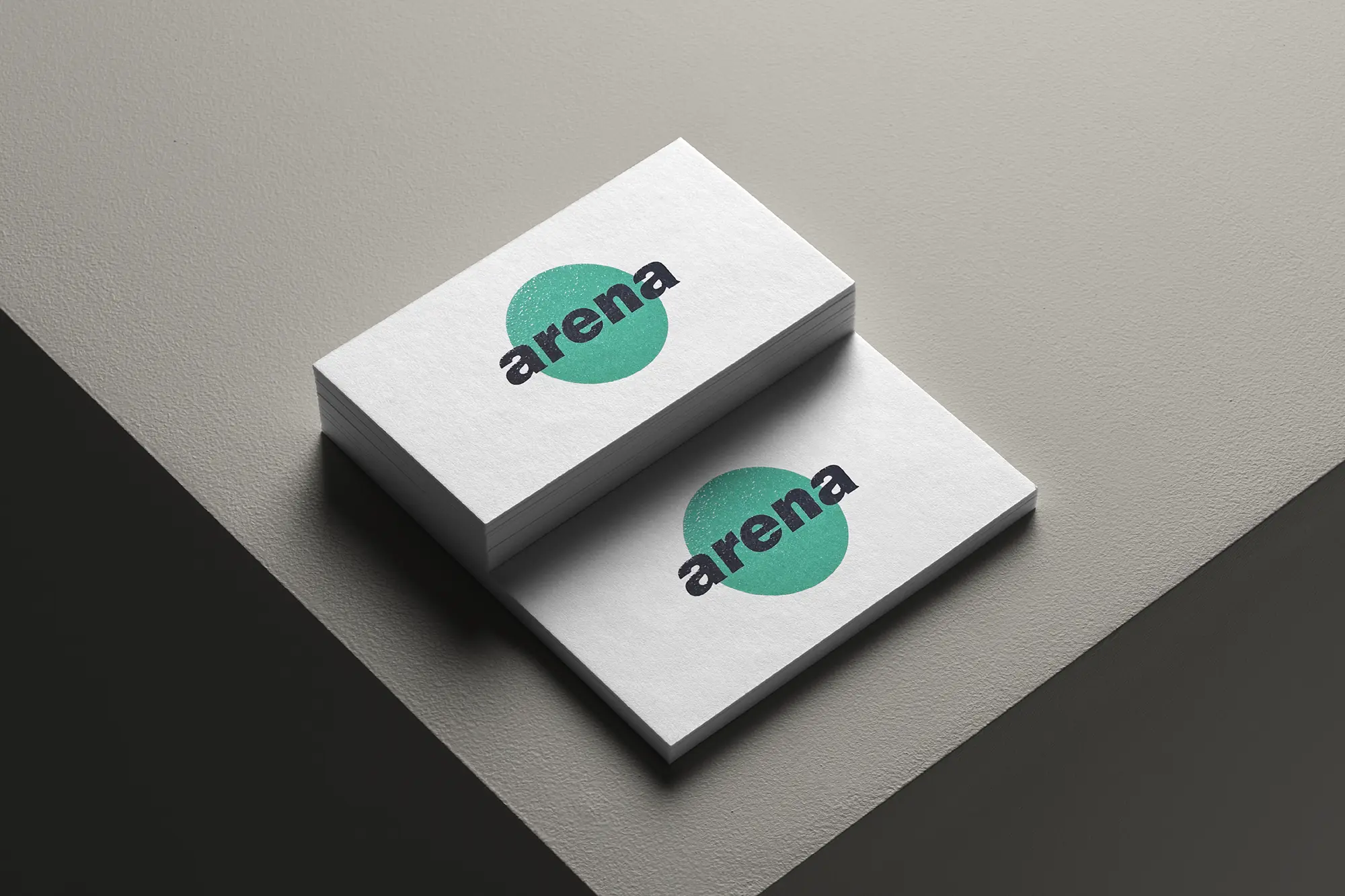 Close-up of stacked white business cards with a vibrant green "arena" logo, showcasing the tactile raised ink texture and crisp edges available at our print studio.