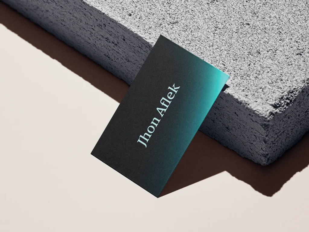 Premium business cards with a custom gradient, locally printed on 18pt suede cardstock and leaning against a textured grey block.