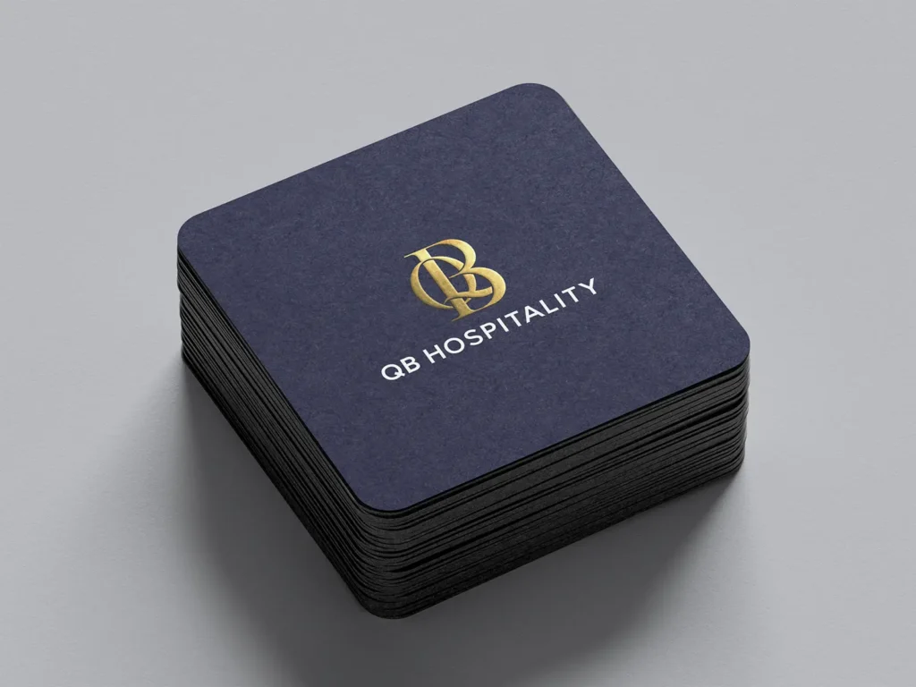Thick navy square coasters with a gold foil logo, produced in our NYC shop for premium hospitality brands and shown in a neat stack.
