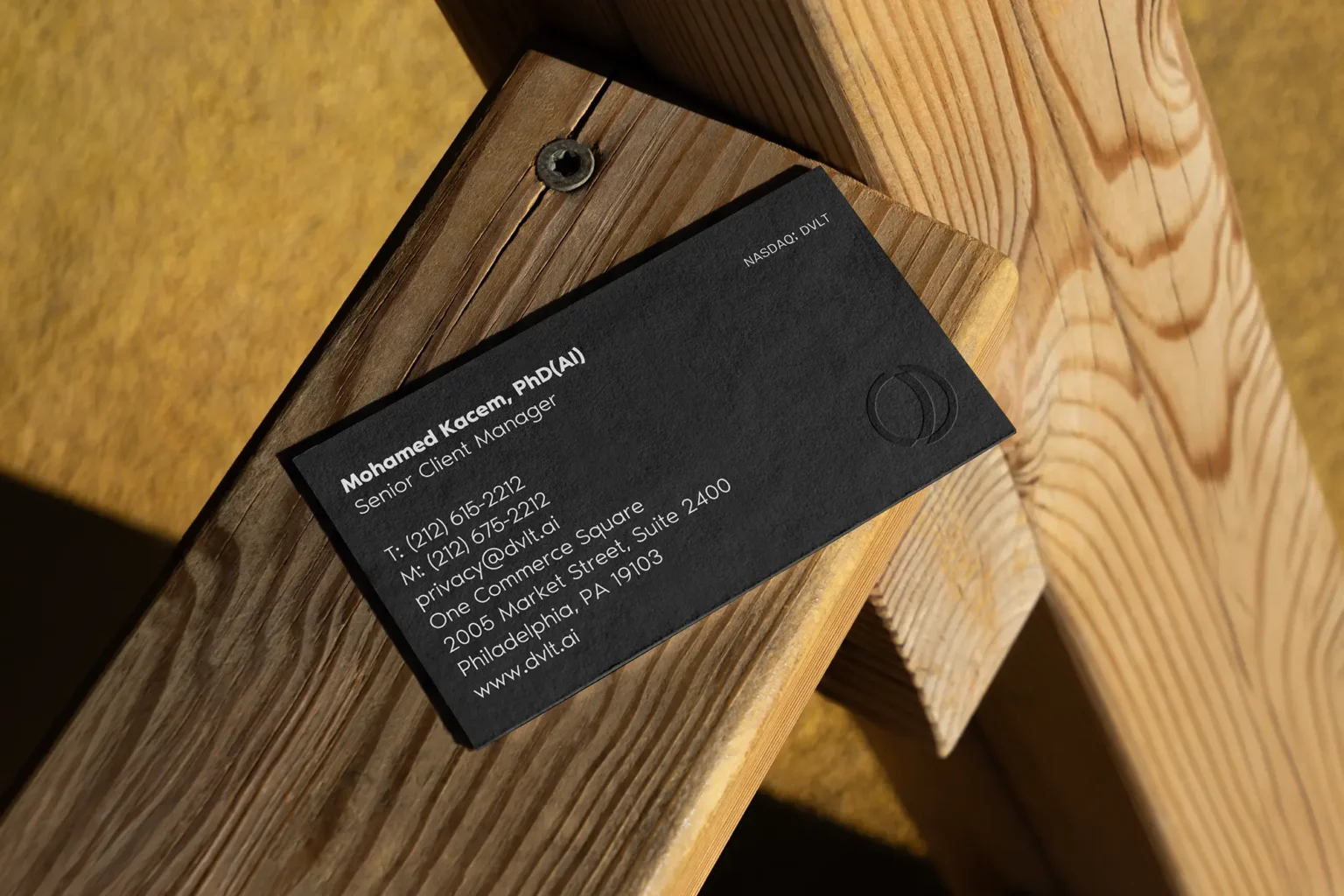 Luxury black business card with black-on-black embossed details displayed on a wooden surface, showing off a modern, architectural style.