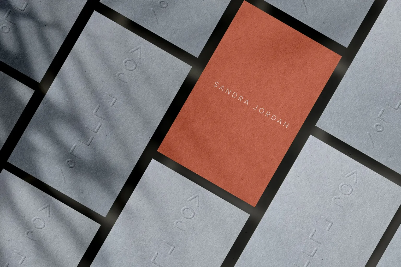 Minimalist terracotta and grey business cards for Sandra Jordan, featuring clean embossed typography that creates a refined and artistic brand presence.