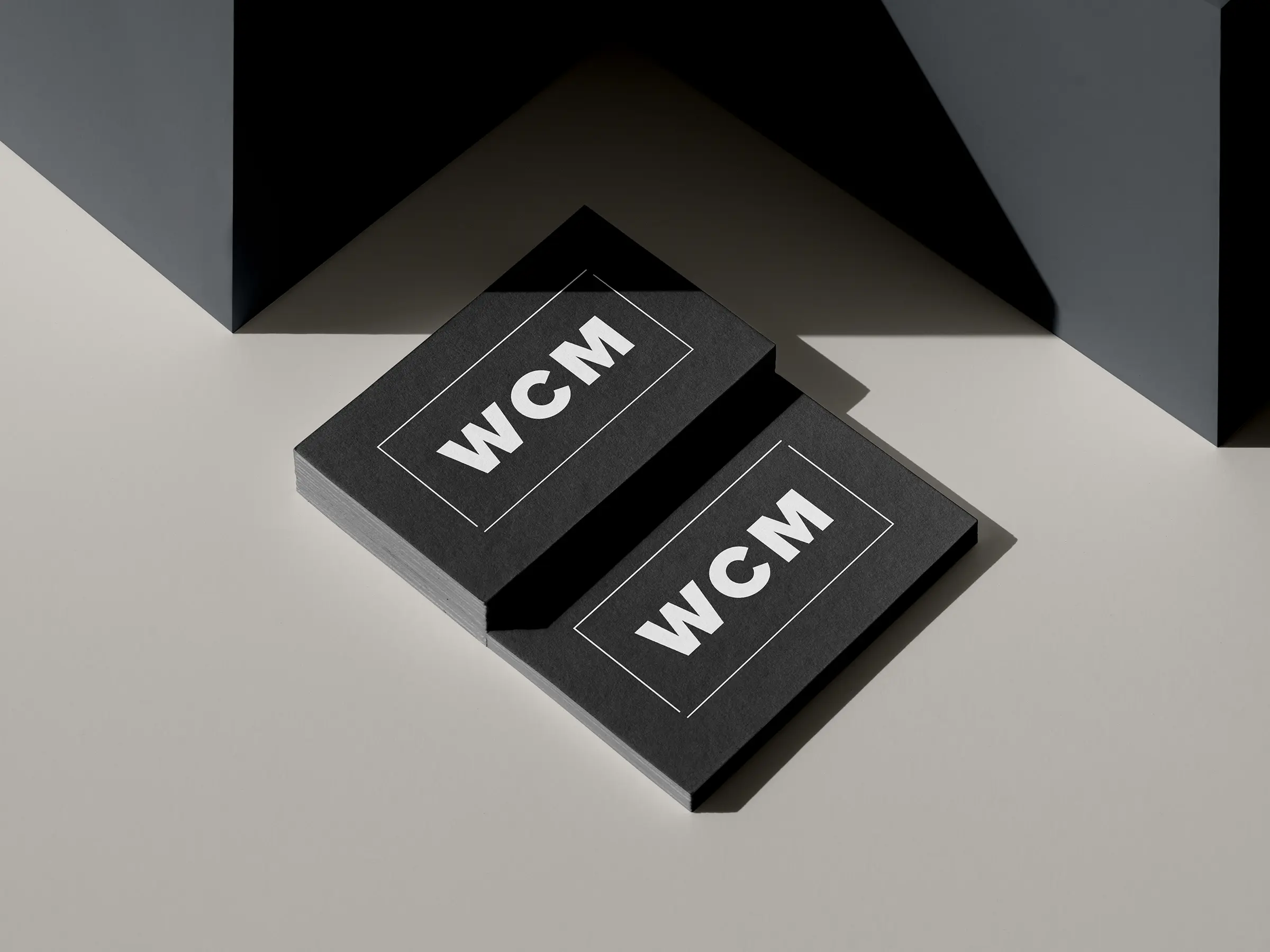 Premium black business cards for WCM featuring white typography and custom painted edges, expertly printed on thick cardstock at our NYC shop to stand out from every angle.
