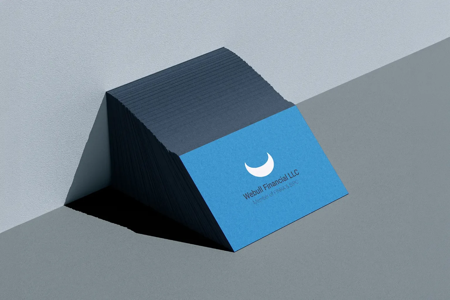A thick stack of blue Webull Financial LLC business cards featuring matching blue painted edges for a seamless, monochromatic professional look.