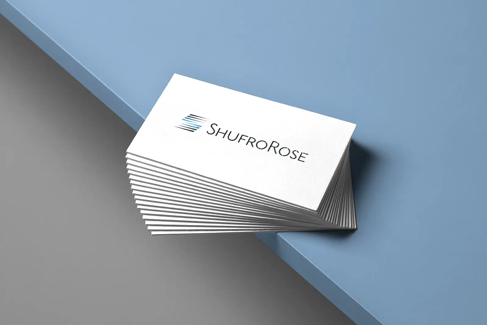 A thick stack of white premium business cards for Shufro Rose with selective shine on the logo, designed for our professional clients throughout the New York area.