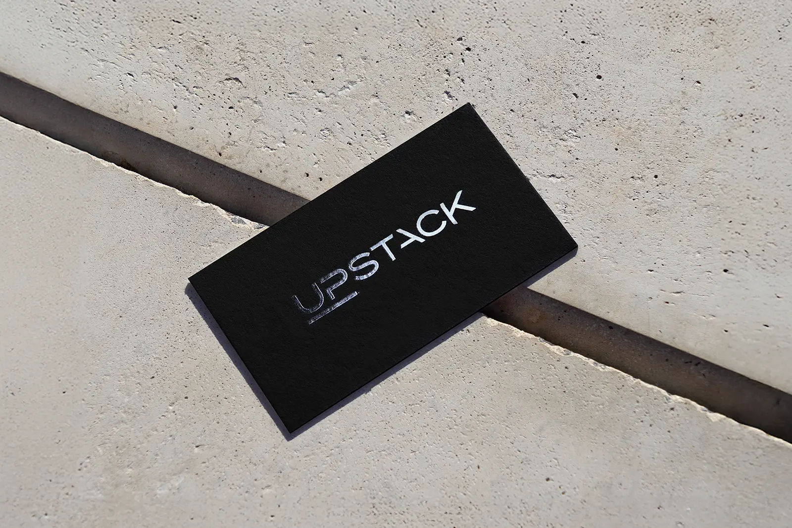 Sleek black minimalist business card for Upstack with a high-contrast spot UV finish on the logo, showcasing the precision gloss available at our NYC studio.