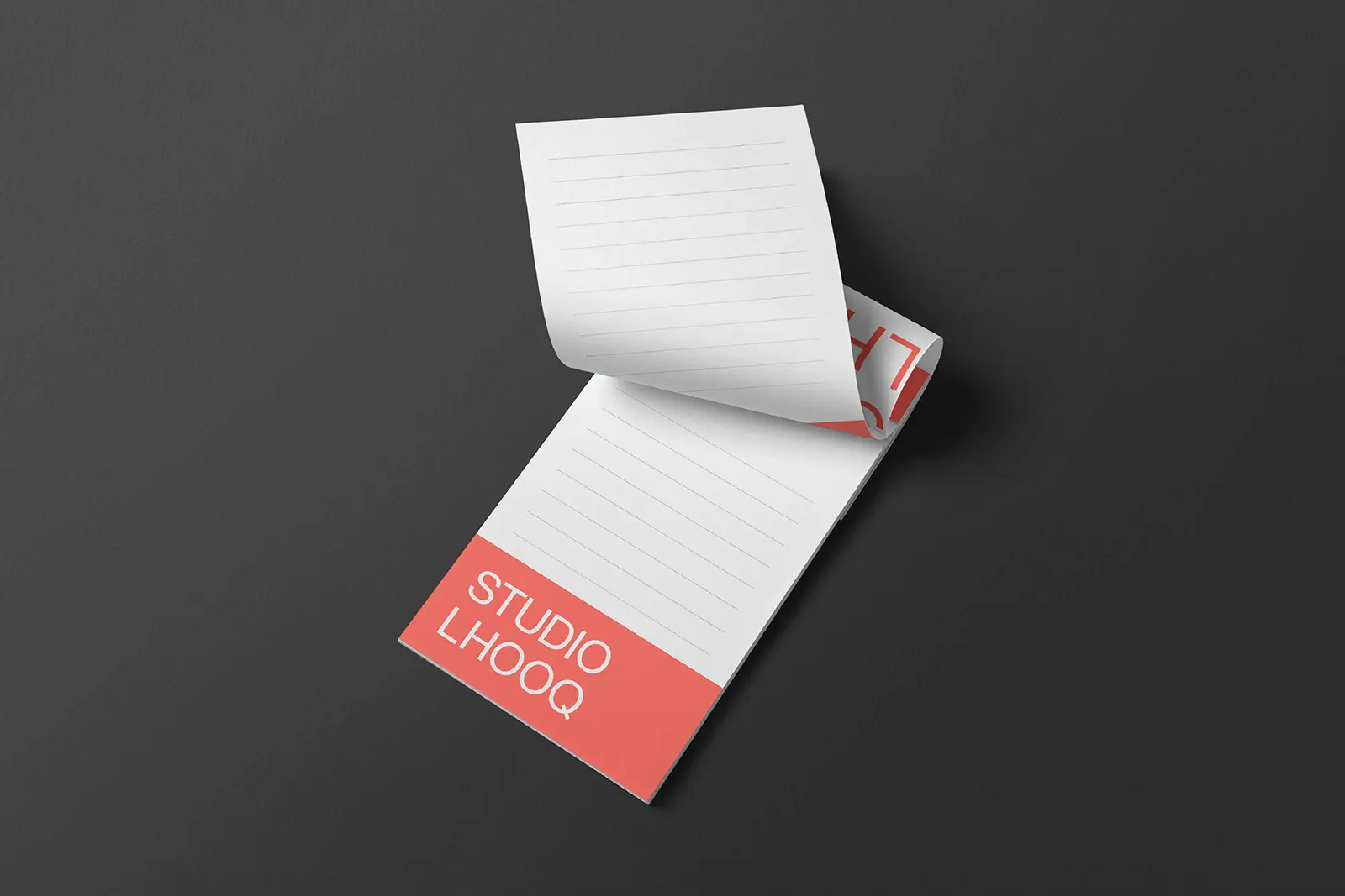 Custom-printed notepad for Studio LHOOQ featuring a bold coral brand logo and lined pages, expertly produced on 70lb High White Text paper at our NYC print shop.
