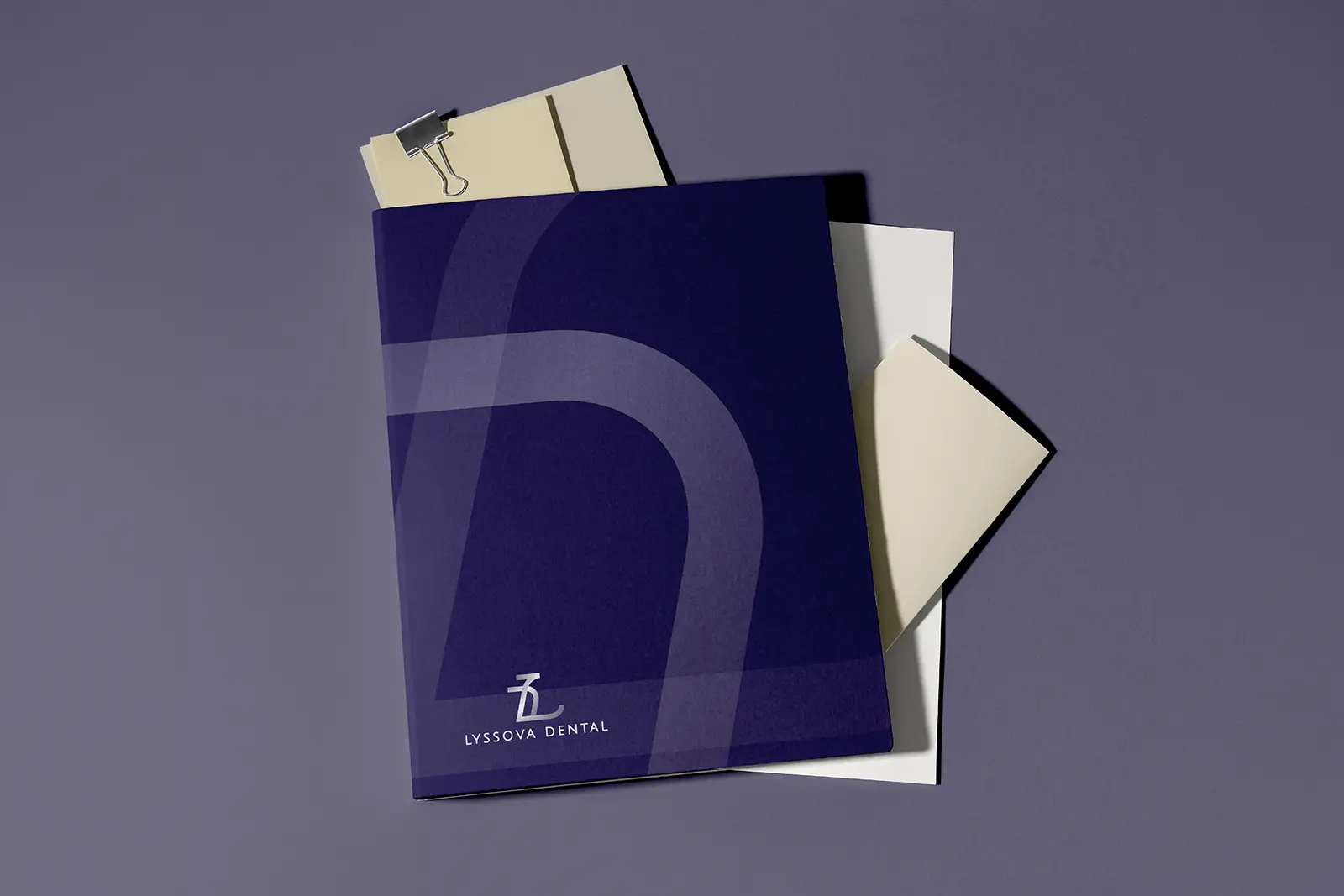 Branded navy blue presentation folders for Lyssova Dental with a large tone-on-tone graphic, custom-crafted in a standard 9x12 inch size with internal business card slits for professional document organization.