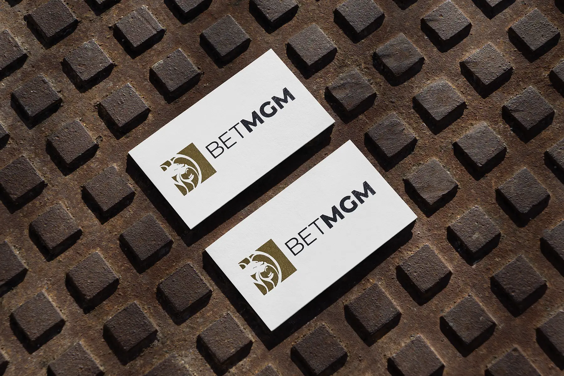 Custom business cards for BetMGM featuring a high-fidelity raised ink logo on 18pt premium matte stock, locally printed at our NYC shop for our corporate clients and photographed on a textured industrial surface.