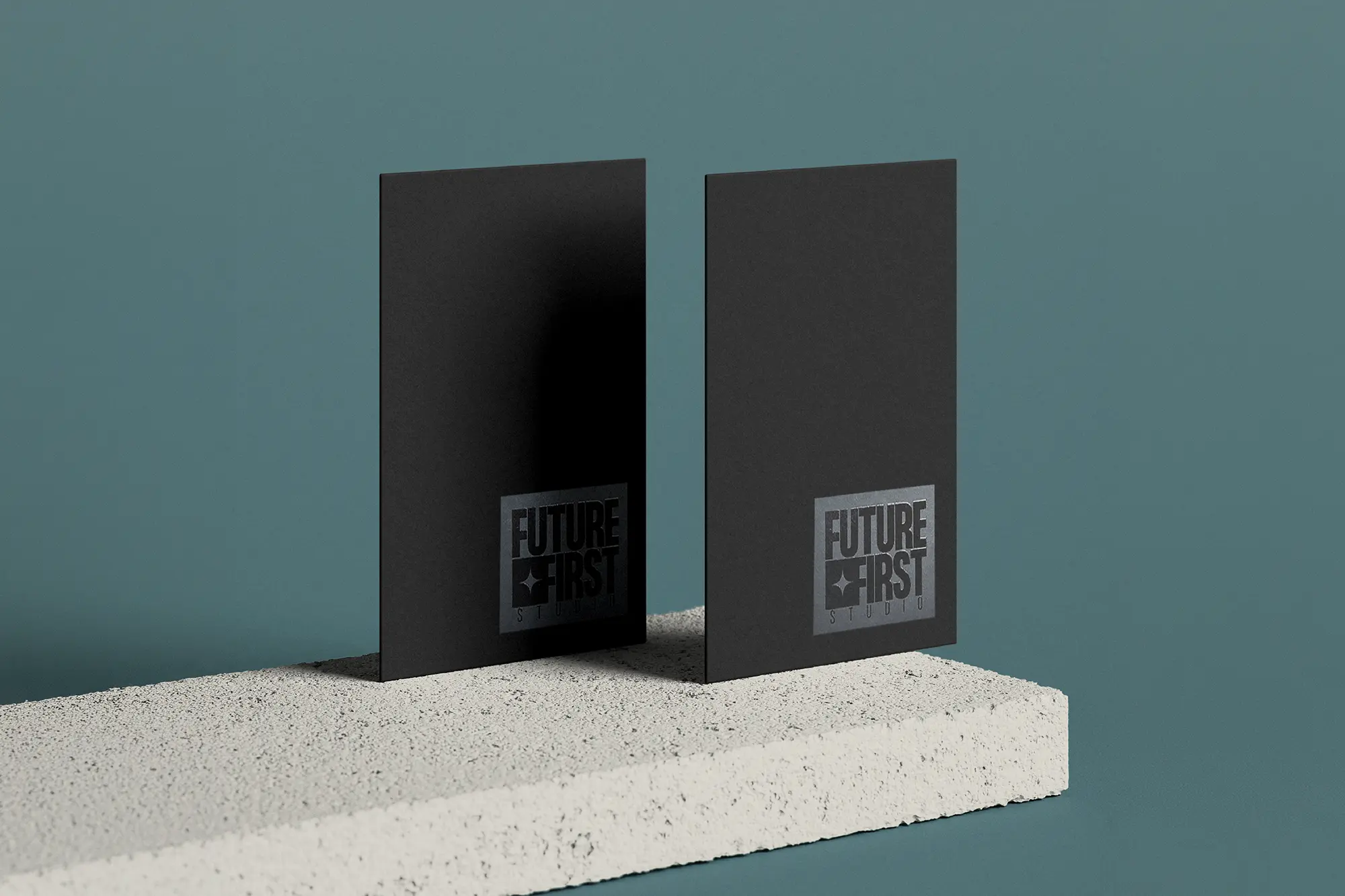 Vertical matte black business cards for Future First Studio featuring a reflective spot gloss box logo, styled on a light concrete block.