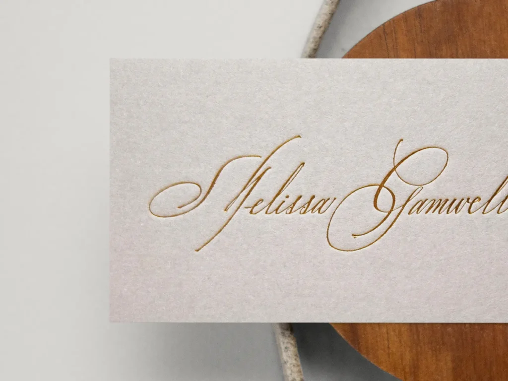 Elegant cream business cards with gold foil script for Melissa Garwell, showcasing the fine detail and tactile quality of our premium foil services.
