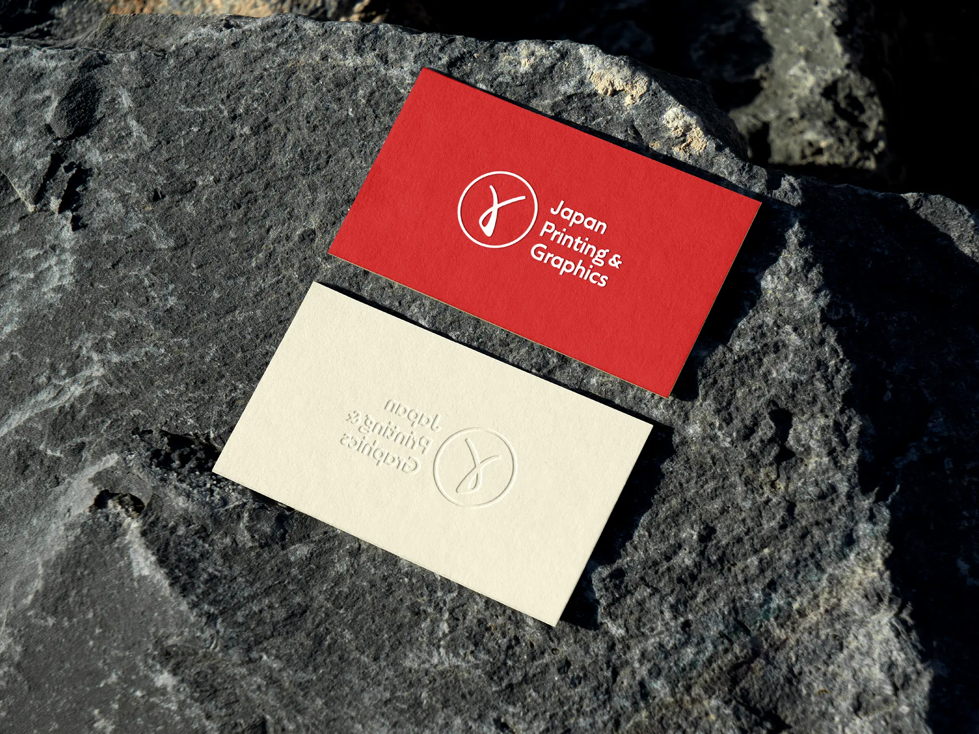 Japan Printing and Graphics Premium business cards featuring a deep deboss on 600 GSM cotton paper styled on a dark stone background.