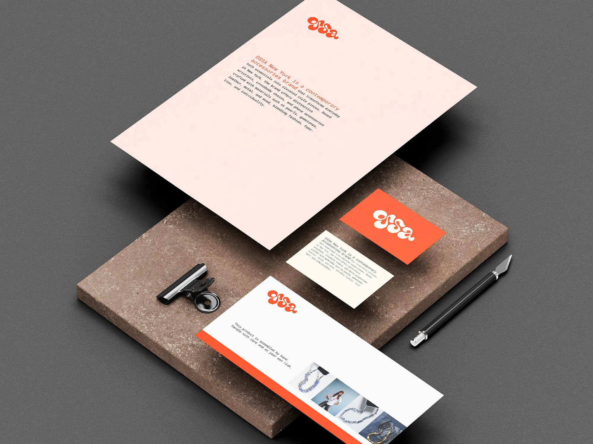 Bespoke corporate stationery including a custom letterhead and matching business cards with orange spot color, locally printed in Manhattan on 24lb Classic Crest paper and styled on a textured block.