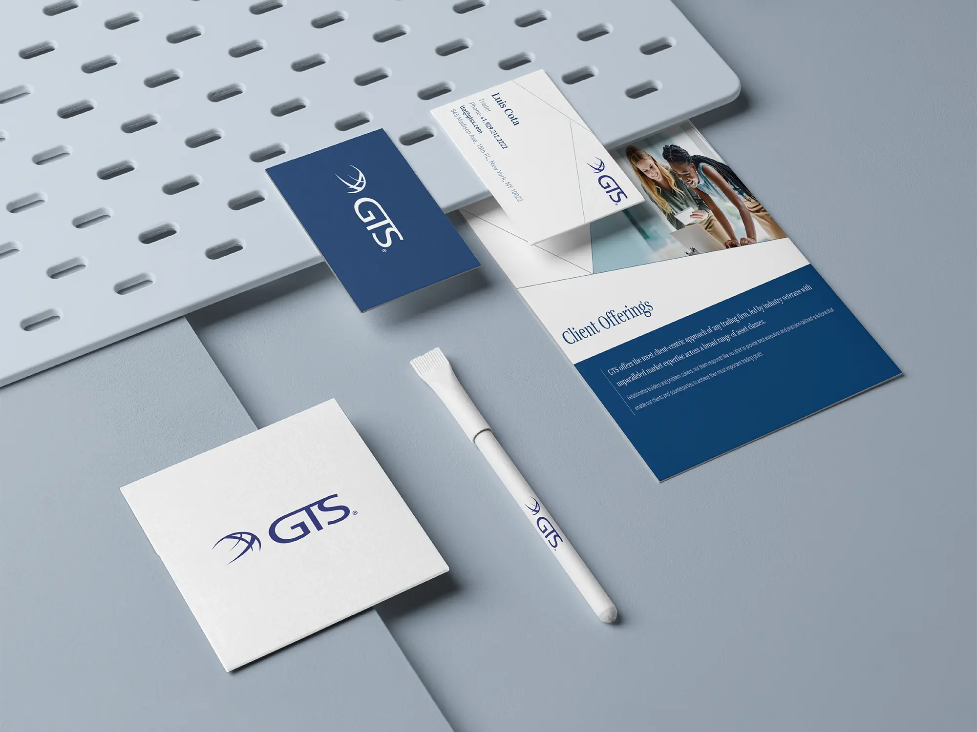 Integrated brand identity materials for GTS, featuring custom printed brochures and business cards on 29pt eggshell matte stock, styled with a branded pen on a grey architectural pegboard.