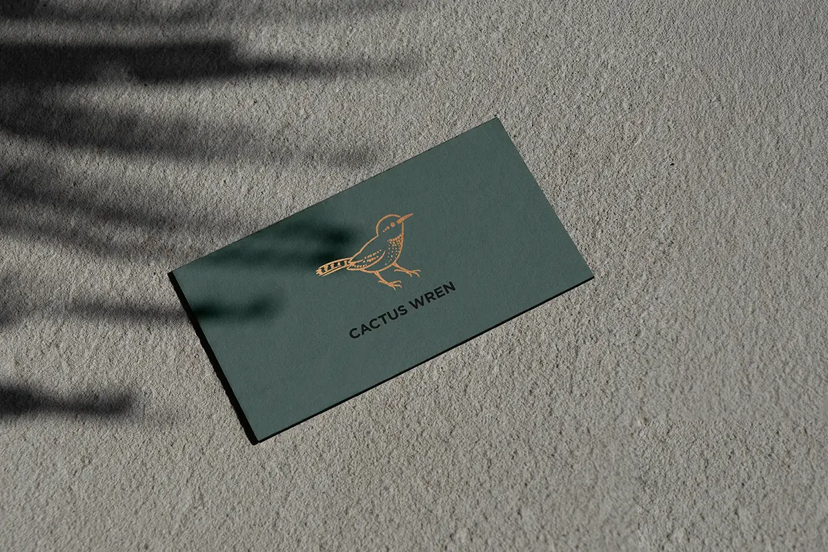 Forest green business card for Cactus Wren featuring a delicate gold foil bird logo, custom-printed using traditional foil stamping at our NYC facility.