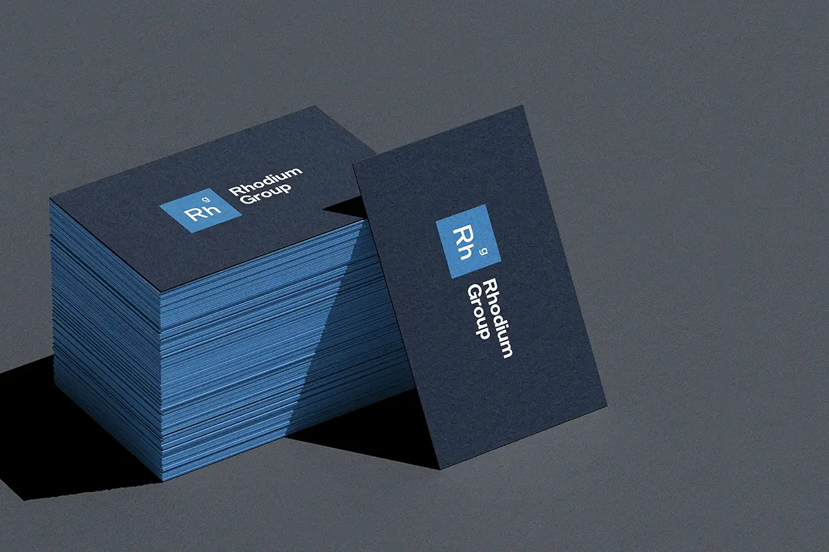 Deep navy Rhodium Group business cards with contrasting light blue colored edges, showcasing the precision of our NYC-based specialty printing services.