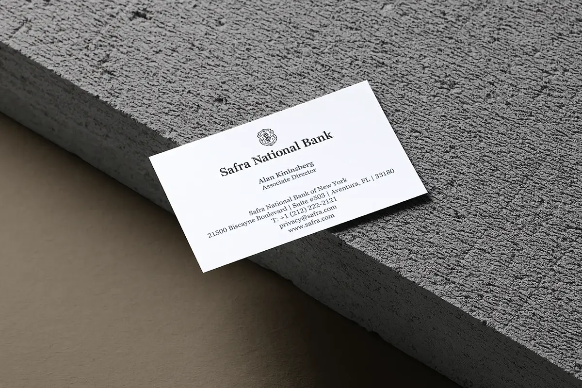 Professional corporate business cards for Safra National Bank, featuring classic navy raised ink for a sophisticated, tactile feel on a textured granite-style background.